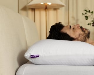 A man sleeps on his back on a Purple pillow