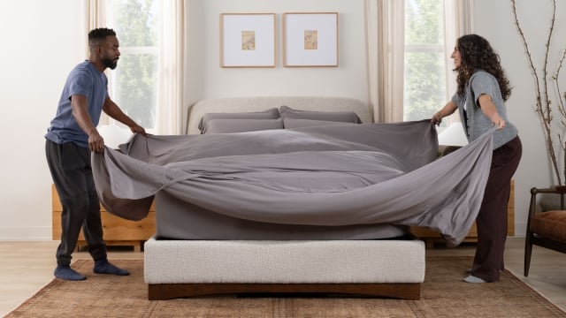Couple making the bed with SoftStretch sheets