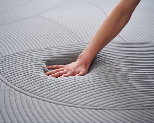 A hand pressing into a Purple RestorePlus mattress.