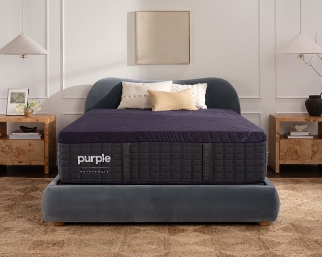 A Rejuvenate mattress on a gray upholstered platform bed.