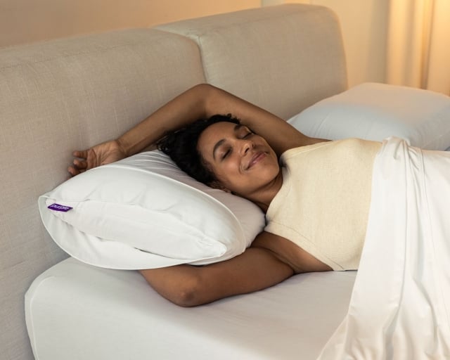 A woman sleeping comfortably on a Purple Harmony pillow.