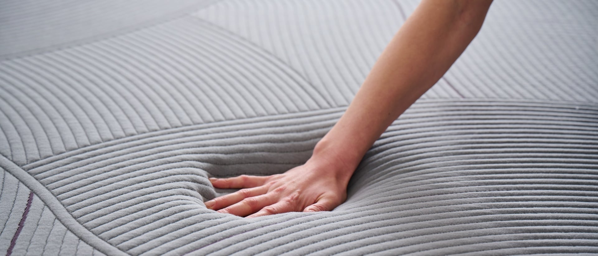 A hand pressing into a Purple RestorePlus mattress.