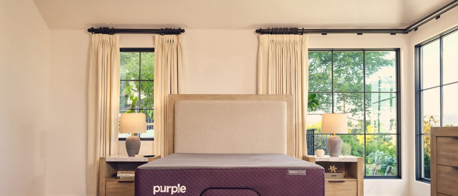 A Purple RestorePremier Hybrid mattress on an upholstered bed frame.